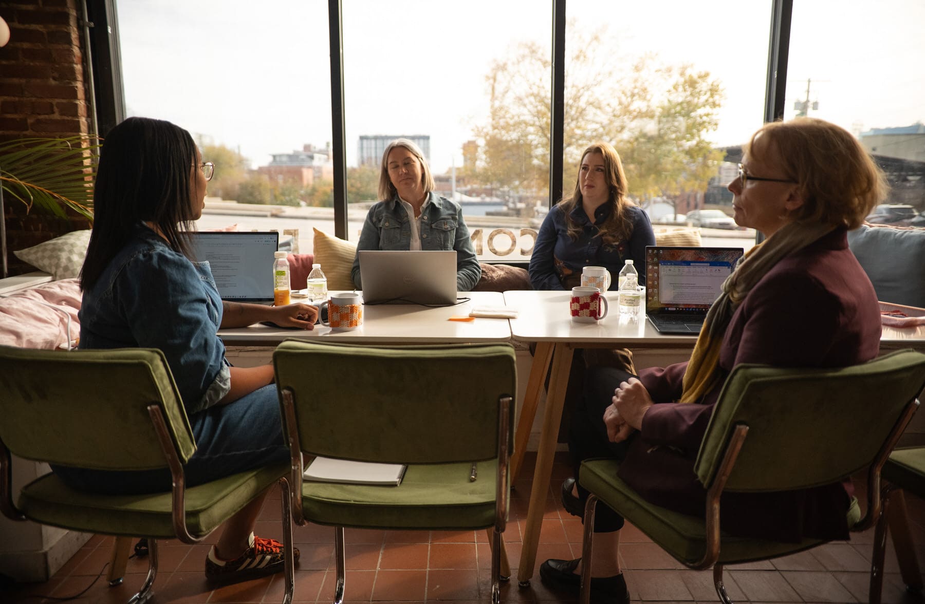 The Elevate team talking at a desk with their computers open about place-based learning and evaluation