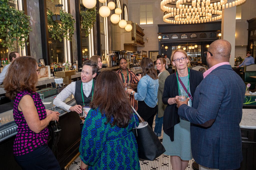 People talking and holding their drinks at Elevate's event for funders of place-based learning and evaluation
